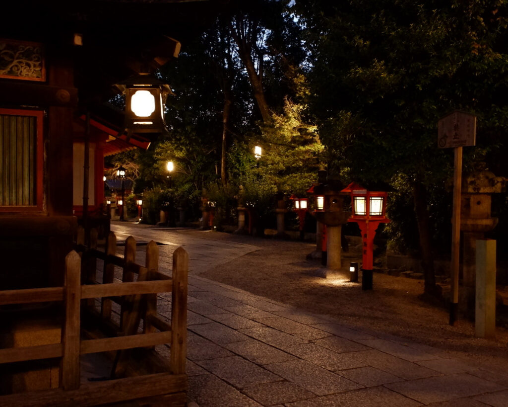 夜の八坂神社の境内。暗い中に灯籠の灯りがありすこし幻想的。